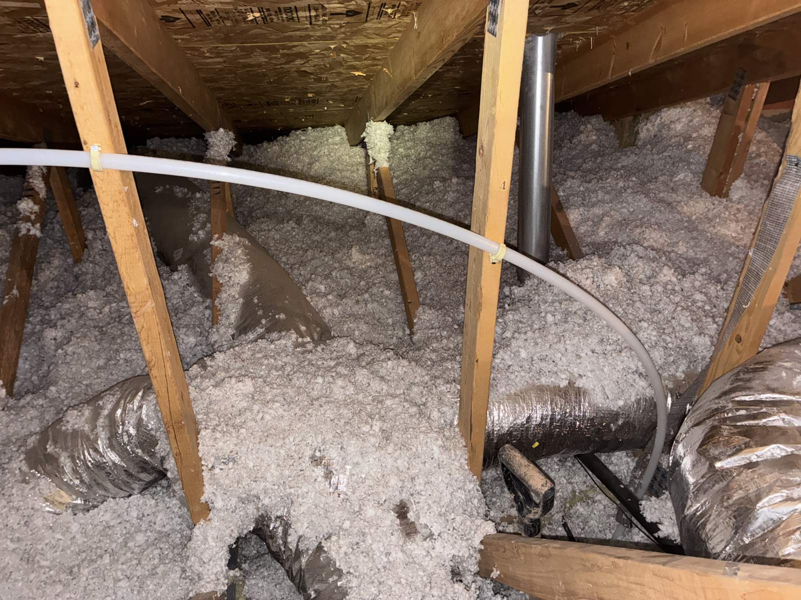PEX water line routed across an attic between ducts and insulation baffles