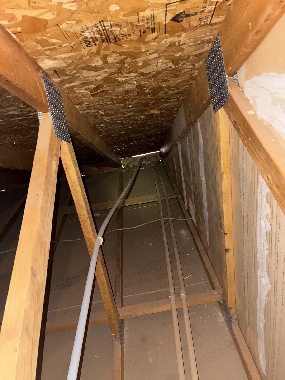 Flexible PEX water line routed through attic trusses above insulation baffles