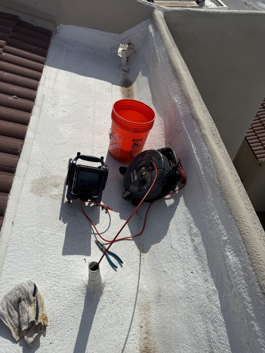 Sewer camera reel and monitor set up on a flat roof beside a vent pipe