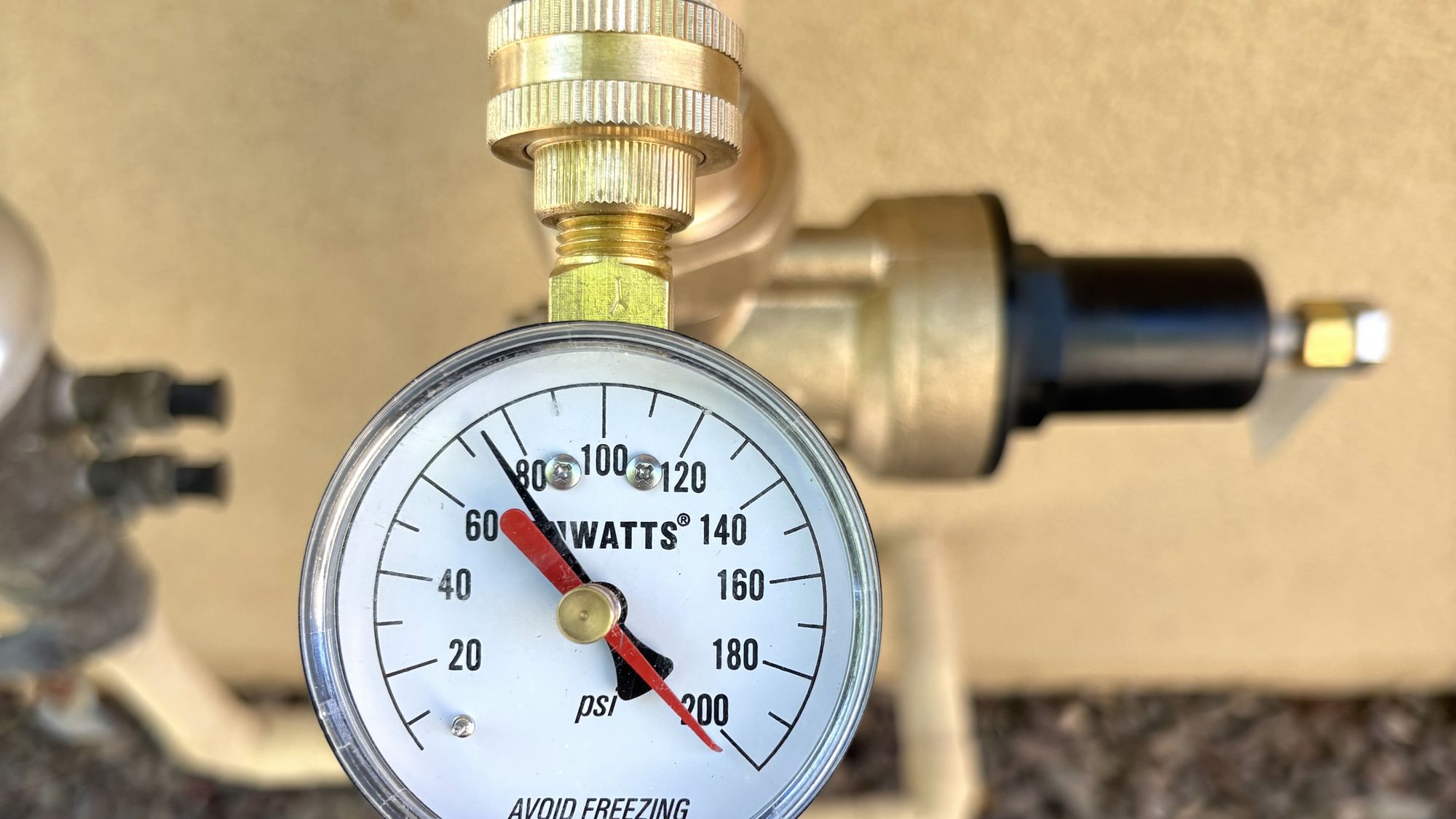 A water pressure test gauge fitted to a hose bib, reading above eighty psi