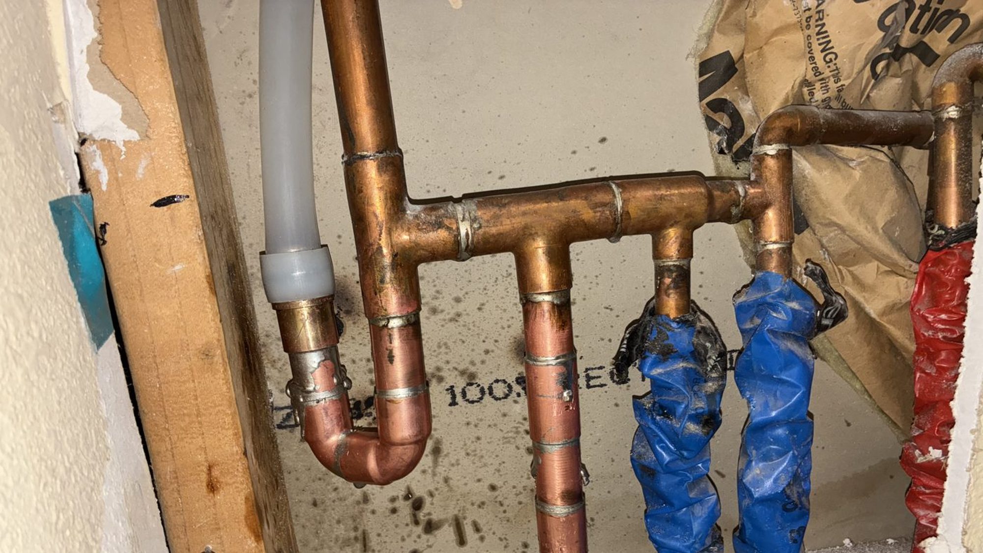 Copper supply manifold with soldered tees and new stub-outs in an opened wall during a repipe