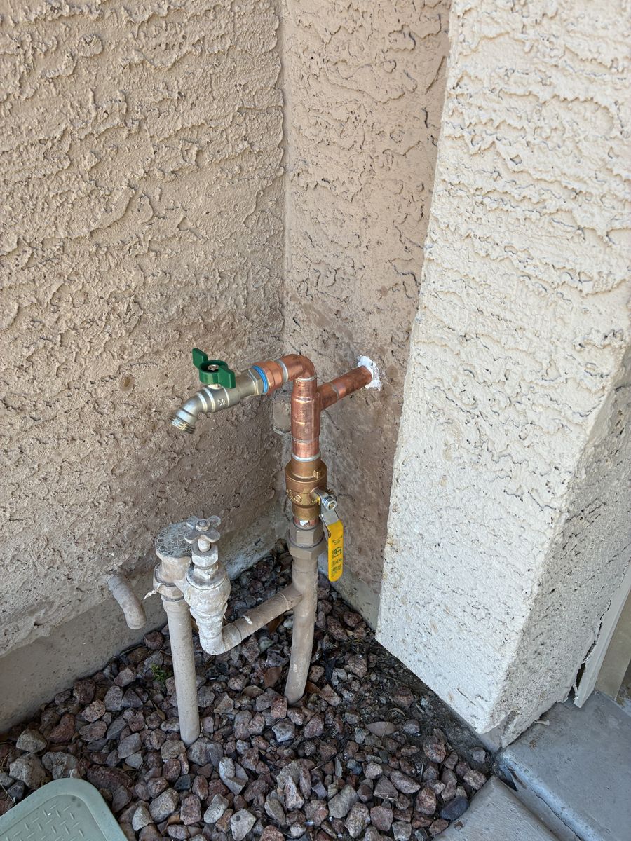 New copper hose bib with a brass ball valve on a stucco exterior wall