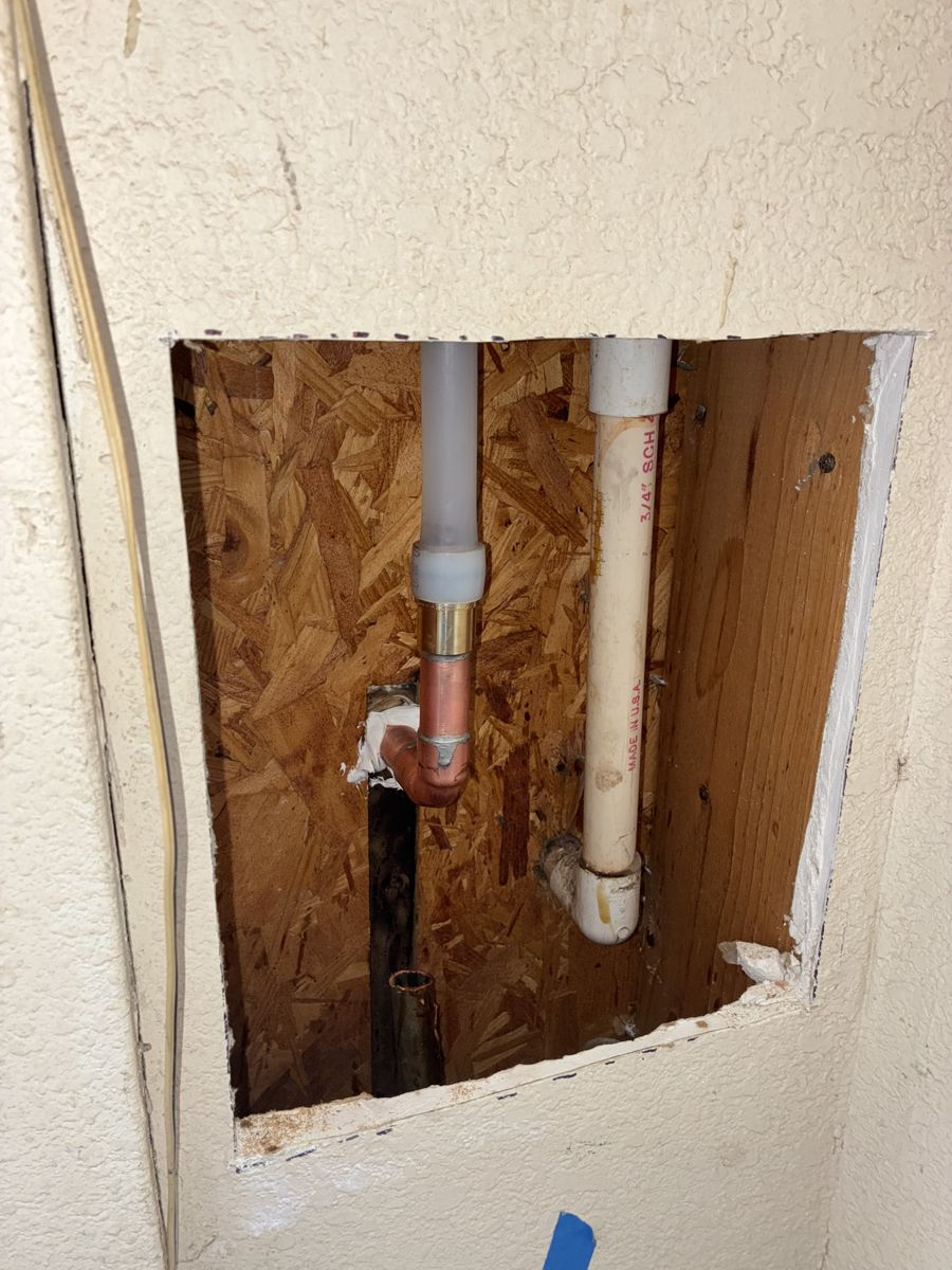 PEX to copper transition fittings and a PVC drain in an opened wall cavity