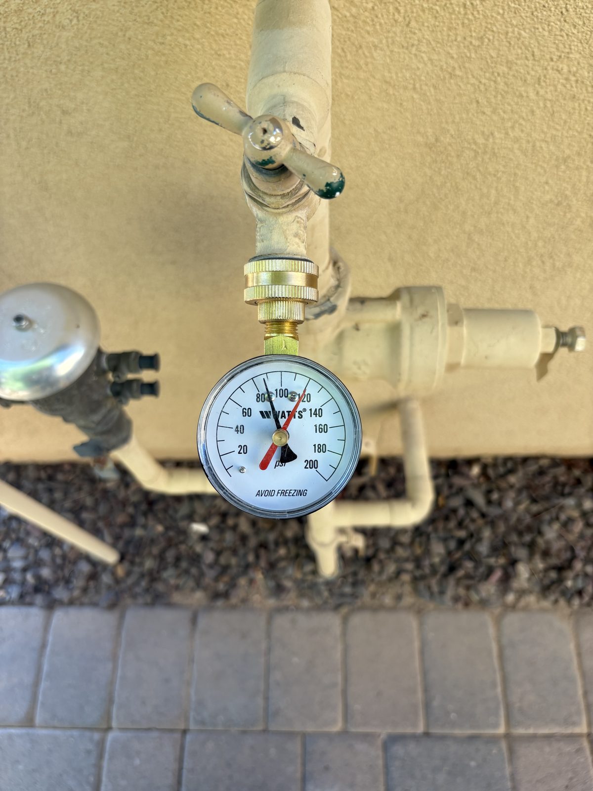 Water pressure test gauge reading above eighty psi next to a backflow assembly
