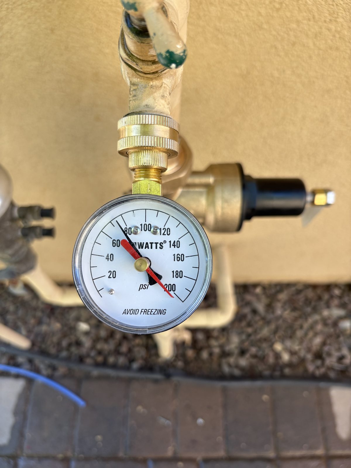 Watts test gauge on a hose bib reading above the eighty psi mark
