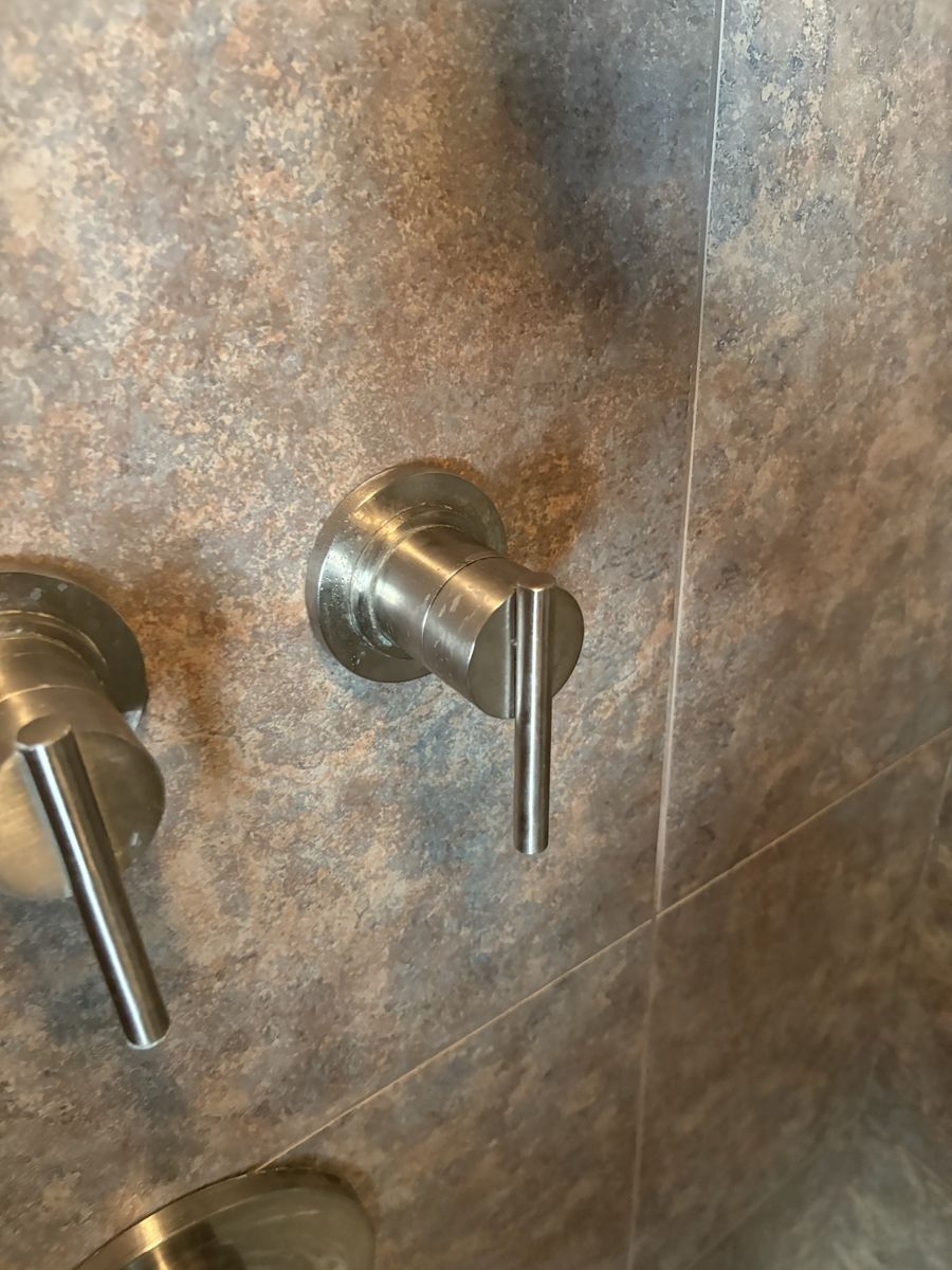 Close-up of a new single-handle shower valve trim on white subway tile
